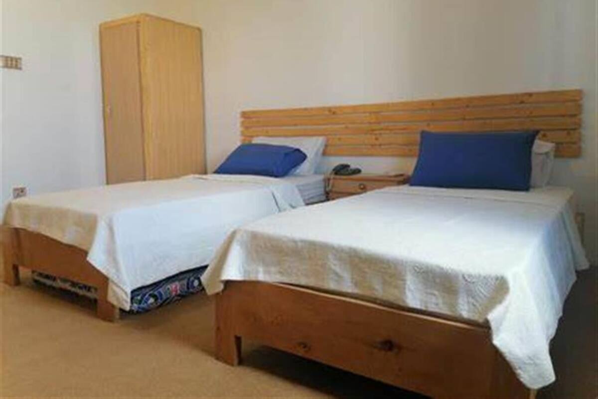 Two single beds with wooden headboards, a wardrobe, and a bedside table with a lamp.