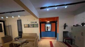 Un salón con sofá, una mesa de centro y una alfombra roja. Hay una puerta que conduce a otra habitación.