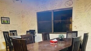 Un área de comedor con una mesa y sillas de madera, una ventana y paredes cubiertas de notas escritas a mano.