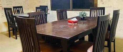 A dining area with a wooden table and chairs, a window, and walls covered with handwritten notes.