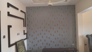 Une pièce avec un papier peint à motifs, un ventilateur de plafond et un banc.