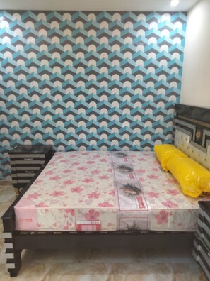 A bedroom with a patterned wallpaper, a bed with floral bedding, and a yellow pillow. - Inviting 3-bed House in Jhelum (Jhelum)