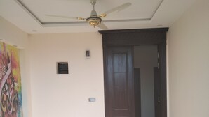 Une pièce dotée d’un ventilateur de plafond, d’une porte en bois et d’un sol carrelé.