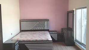 Une chambre à coucher comprenant un lit, une commode et une armoire, avec un mur et un plafond de couleur rose.