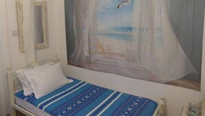 Quarto com cama, janela com vista para a praia e espelho na parede.