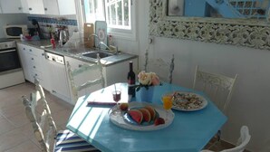 Uma cozinha com uma mesa azul, cadeiras brancas e uma pia.