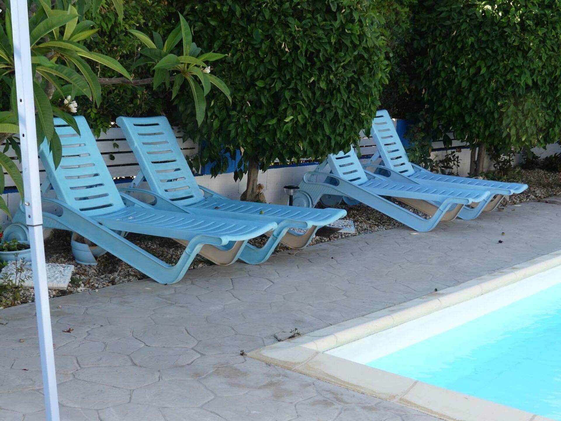 A poolside area with light blue lounge chairs and a swimming pool.