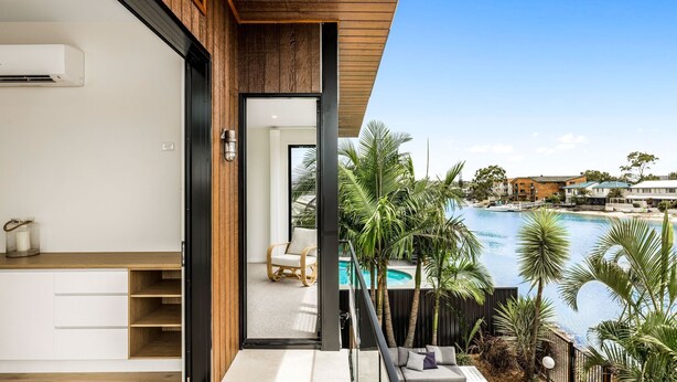 Un balcón moderno con vistas a una piscina y edificios circundantes.