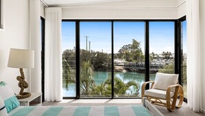 Una habitación con un amplio ventanal corredero que da a vistas de un puerto deportivo y el agua.
