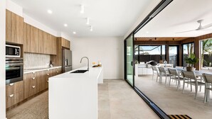 Una cocina moderna con electrodomésticos integrados, una isla grande y una zona de comedor con asientos exteriores.