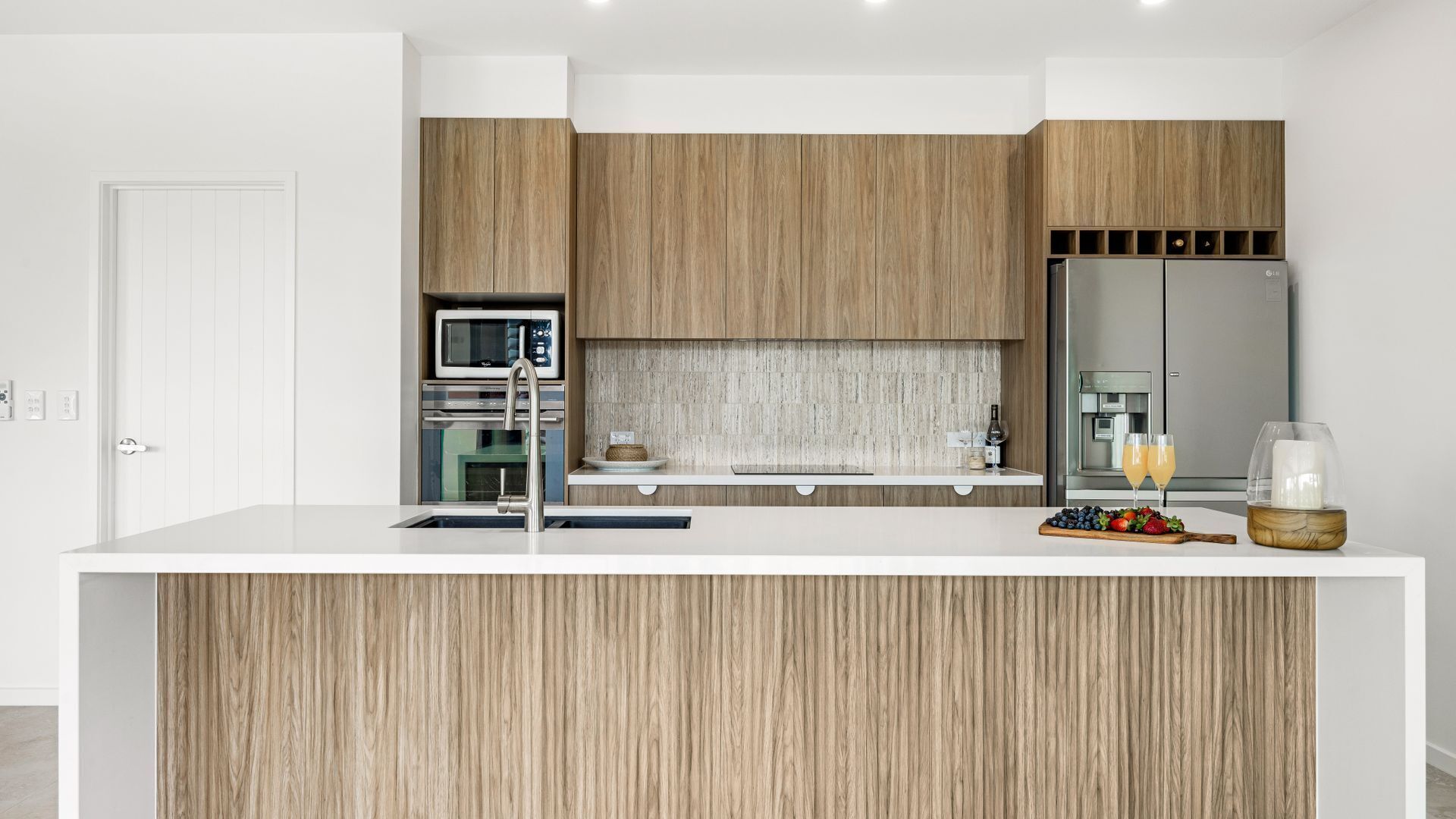 Een moderne keuken met houten kastjes, roestvrijstalen apparatuur en een centraal eiland met een spoelbak.