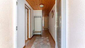 A hallway with wooden ceiling, white walls, and hexagonal patterned floor tiles.