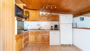 A kitchen with wooden cabinets, a white refrigerator, a dishwasher, and a wooden ceiling.