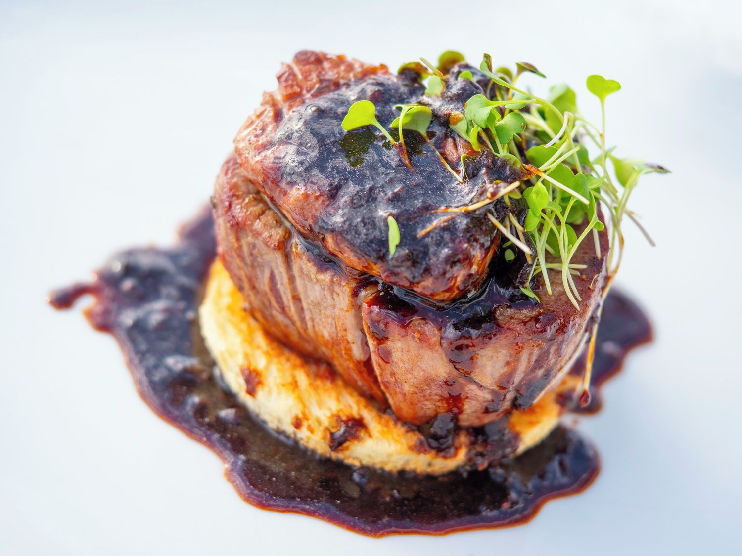A dish with a dark sauce and green garnish.