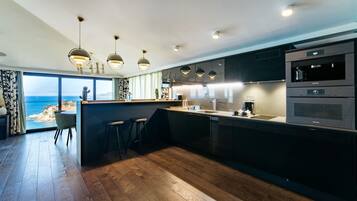 Een moderne keuken met een groot kookeiland, barstoelen en uitzicht op de oceaan.