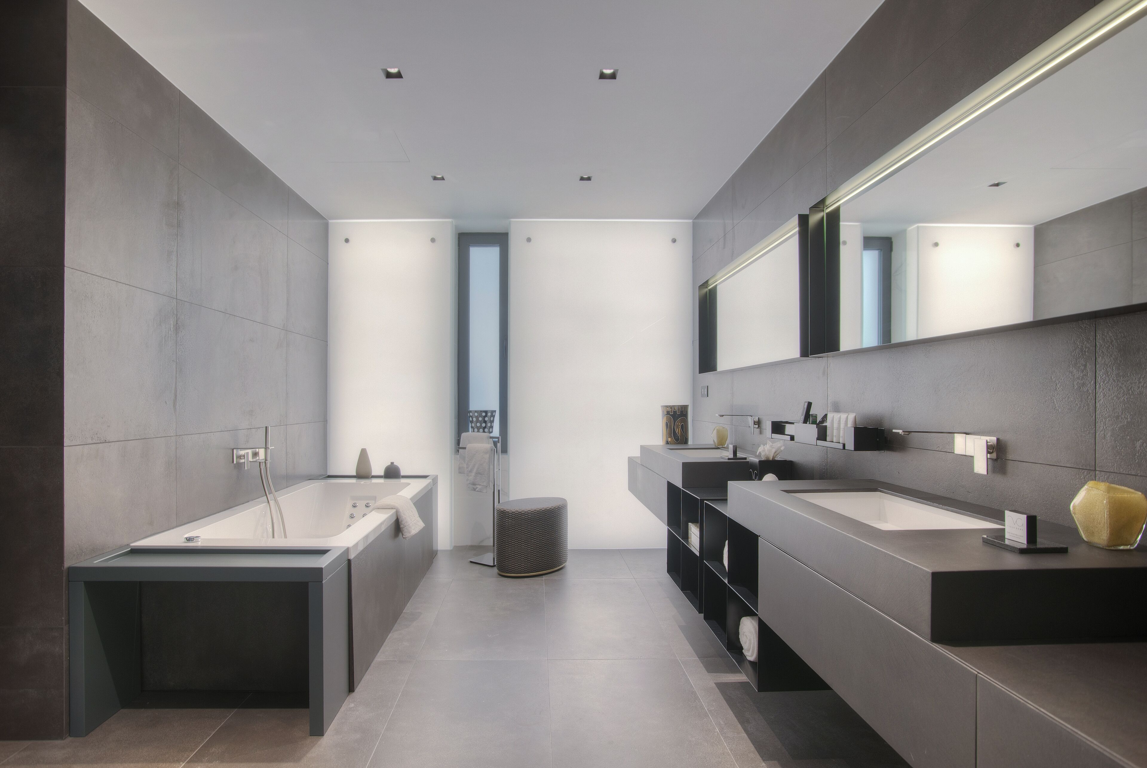 A modern bathroom with a large bathtub, two sinks, and a large mirror.