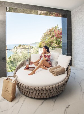 A circular bed with a view of the sea and greenery, a drink on the side, and a towel beside it. - Villa Geba Boutique Hotel (Sveti Stefan)