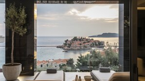 A balcony with a view of a coastal town, a potted plant, and a seating area with a table. - Villa Geba Boutique Hotel (Sveti Stefan)
