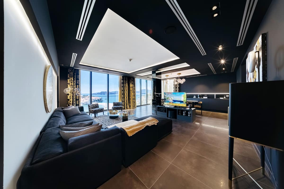 A modern living room with a large sectional sofa, a dining area, and a kitchen.