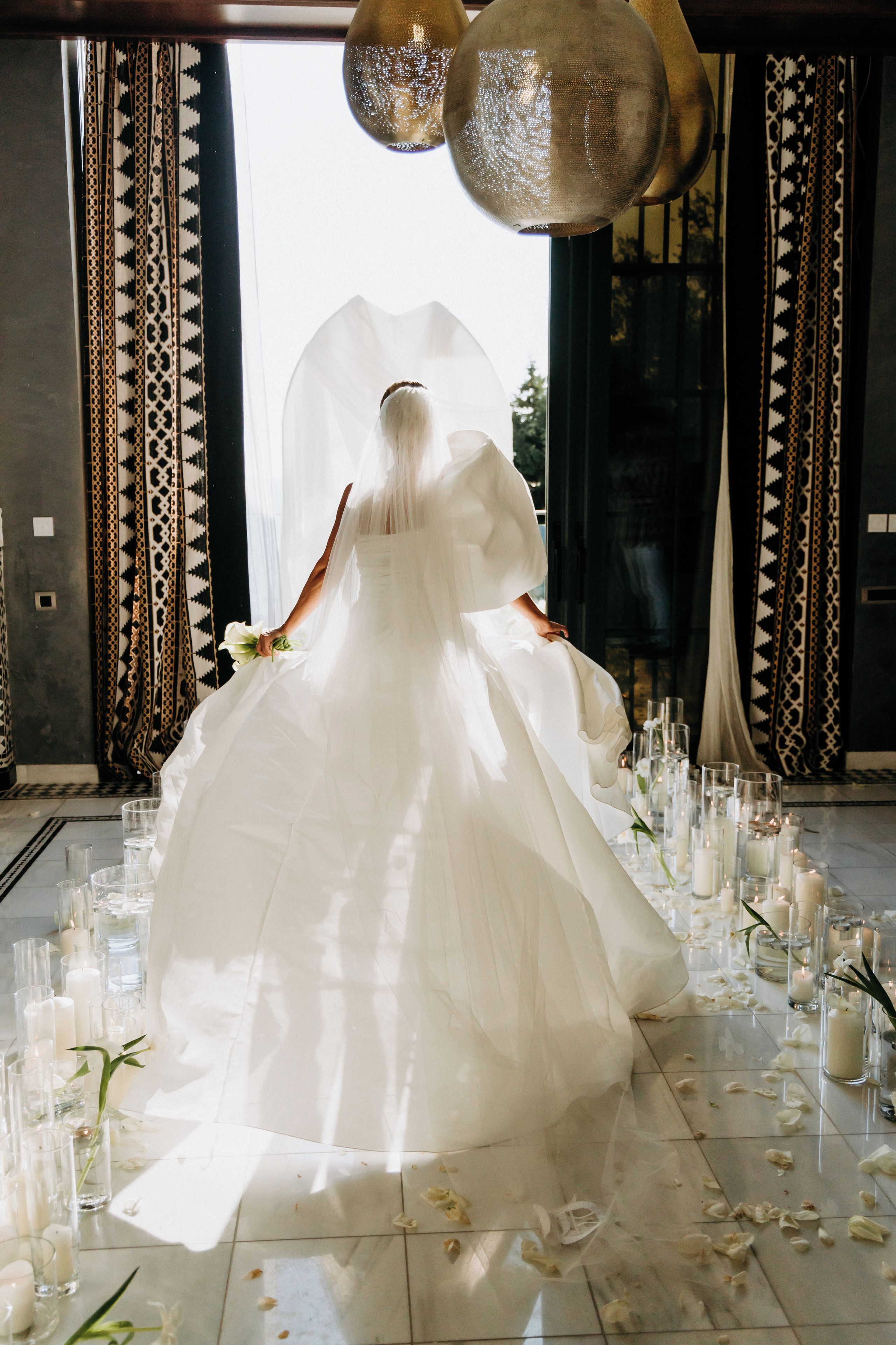 A wedding dress on display with a floor covered in rose petals and candles.