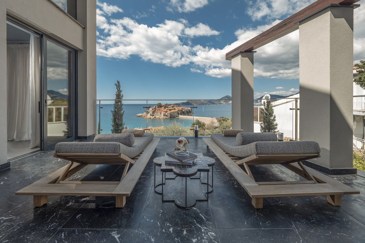 A balcony with a view of the sea and a mountainous landscape.
