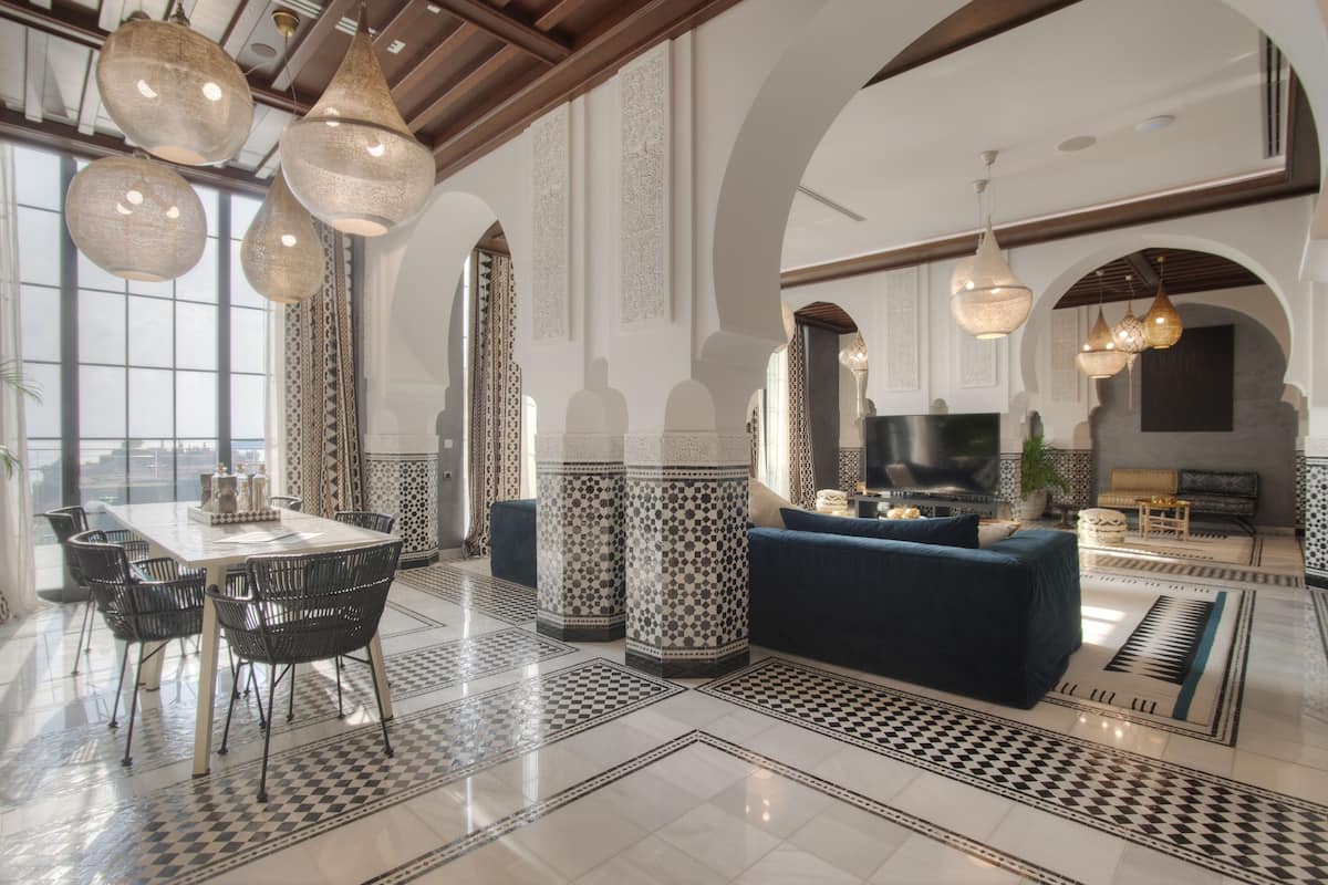 A spacious living area with a large sofa, a dining table with chairs, and a TV.