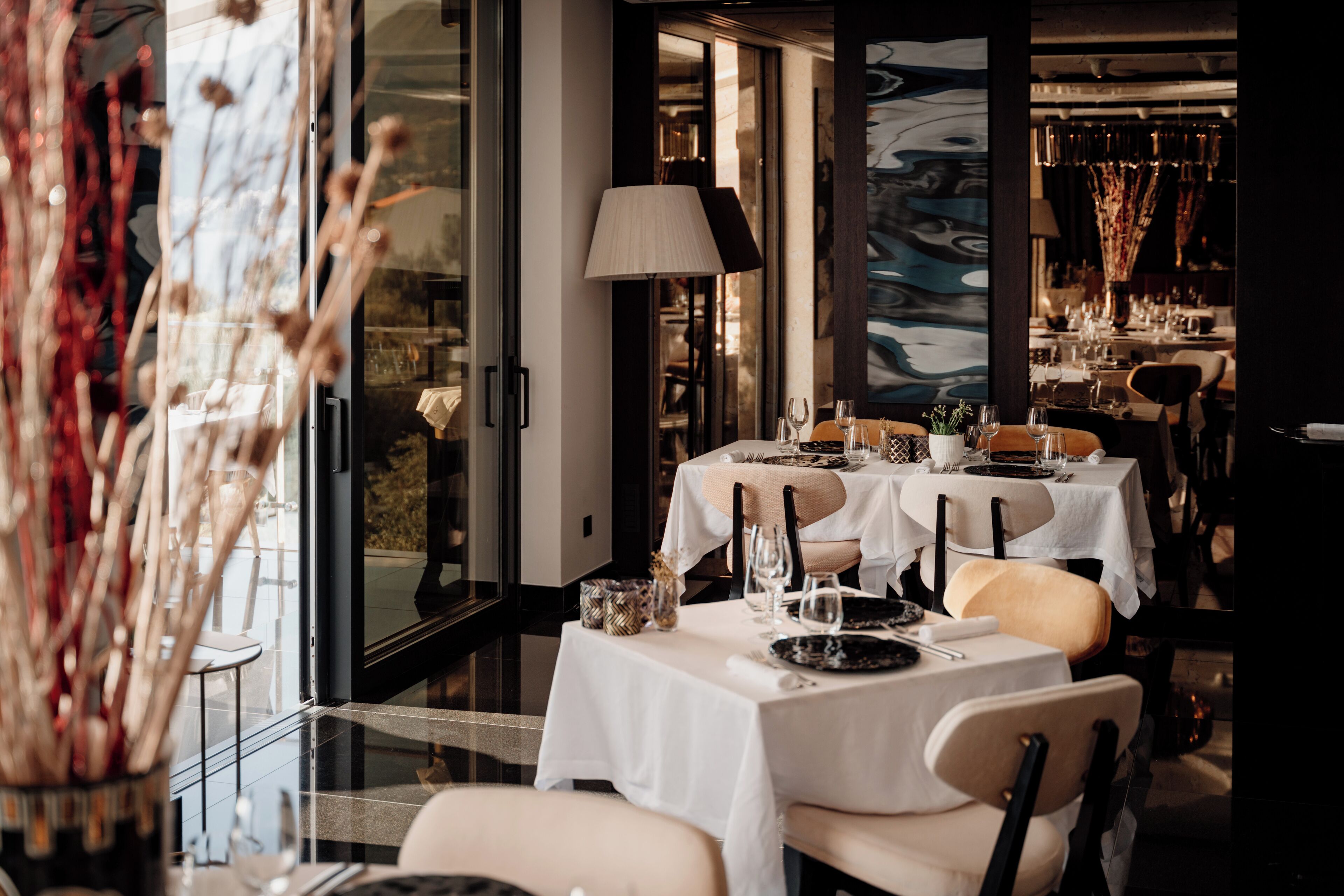 Un restaurante con mesas dispuestas para comer, un amplio ventanal y una decoración interior moderna.