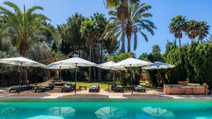 A poolside area with lounge chairs and umbrellas, surrounded by palm trees. - Villa La Torre: historic watchtower with pool and restaurant at agrotourism resort (Campos)