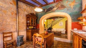 A dining area with a stone wall, wooden furniture, and a mural. - Villa La Torre: historic watchtower with pool and restaurant at agrotourism resort (Campos)