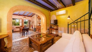 A spacious living area with a wooden coffee table, white sofa, and a stone archway leading to an outdoor patio. - Villa La Torre: historic watchtower with pool and restaurant at agrotourism resort (Campos)