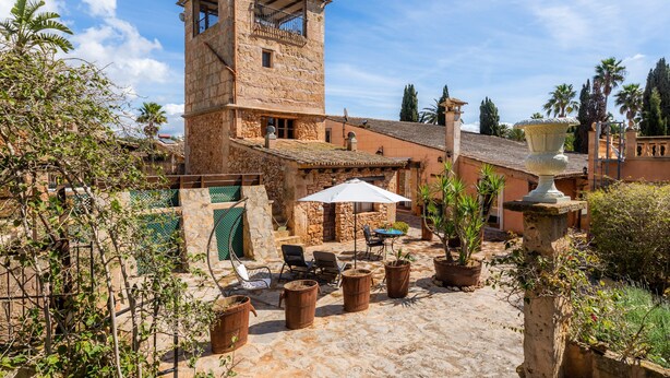 A stone building with a tower, outdoor seating, and potted plants. - Villa La Torre: historic watchtower with pool and restaurant at agrotourism resort (Campos)