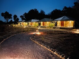 A series of tents with a paved path leading to them, surrounded by trees.
