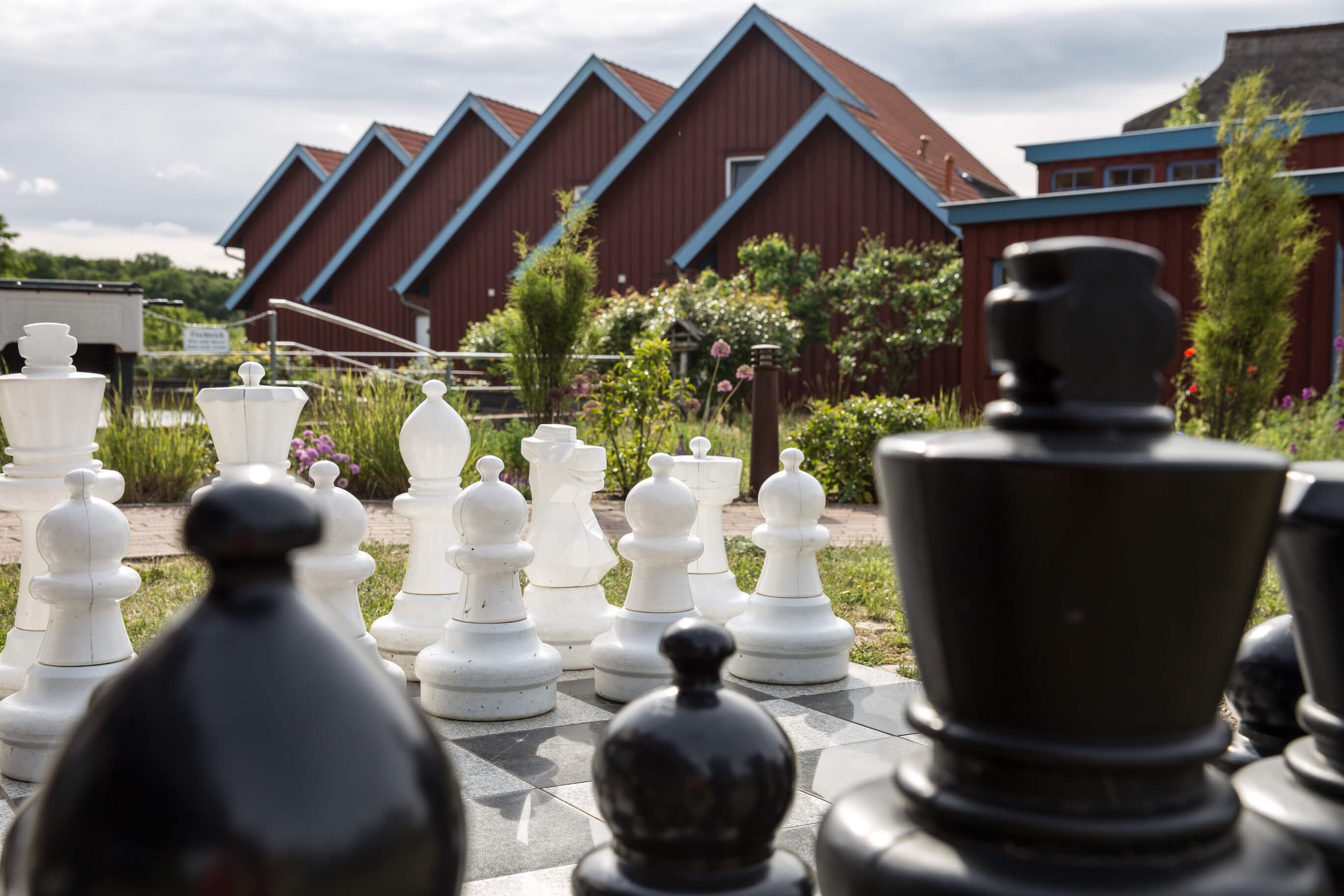 A chessboard set outdoors with a red building in the background.