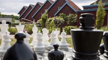 A chessboard set outdoors with a red building in the background.