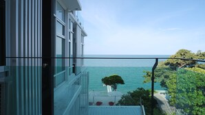Un balcón con vistas despejadas al mar y un árbol.