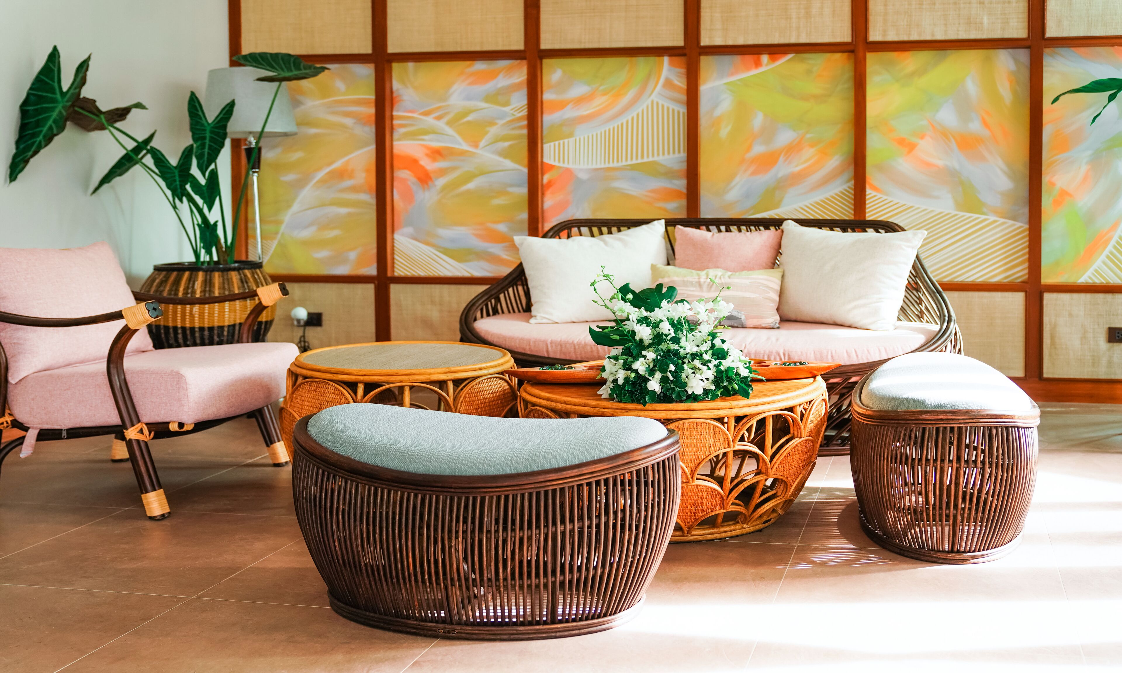 Et traditionelt japansk værelse med tatamimåtter, et lavt bord med hynder, en sofa med hynder og en dekorativ plante.