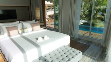 A hotel room with a large bed, a view of a pool, and a balcony with outdoor furniture.