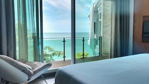 Habitación de hotel con una ventana grande que da a un balcón y al mar.