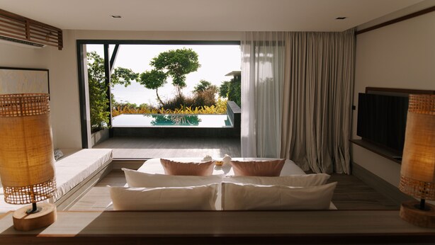 Un dormitorio moderno con una cama grande, televisión y vistas a una piscina y vegetación.