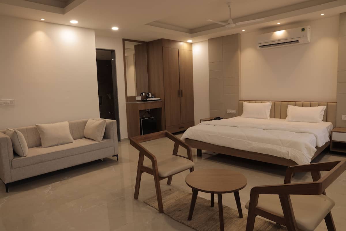 A modern hotel room with a bed, a sofa, a desk, and a chair.