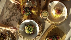 Ein Esstisch mit verschiedenen Gerichten, darunter ein Teller mit Spiegelei, eine Salatschüssel und ein Teller mit Bratkartoffeln.