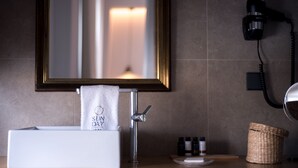 Ein Badezimmer mit Waschbecken, Handtuch, Spiegel, Fön und Pflegeprodukten.