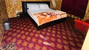 Un dormitorio con cama, ventilador de techo, paredes con diseño y una silla roja.