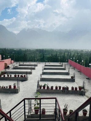 Terraza en la azotea con suelo de hormigón, plantas en macetas y baranda de metal.