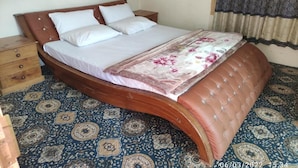 Una cama con cabecera de madera curvada, colcha estampada y alfombra con diseño.