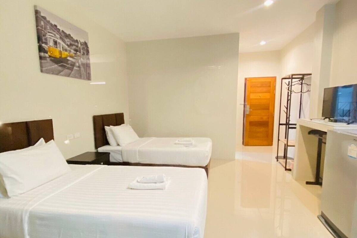 A hotel room with two beds, a flat-screen TV, a coat rack, and a painting on the wall.