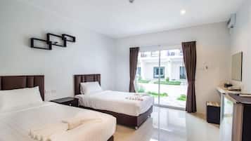 Habitación de hotel con dos camas, un escritorio y vistas al exterior.