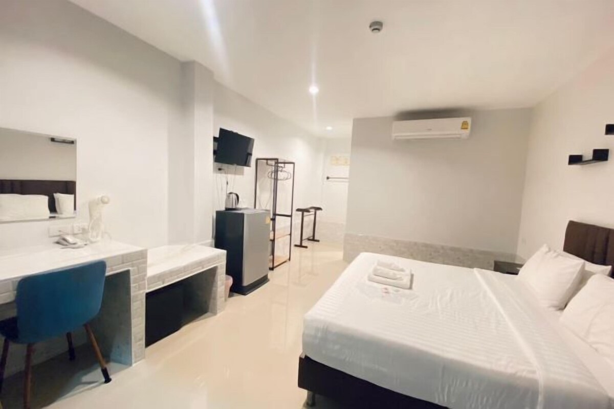 A hotel room with a bed, a desk, a chair, a television, and a wardrobe.