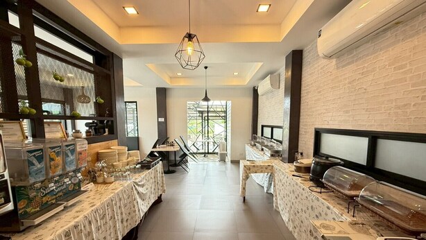 A breakfast area with tables set for dining, a coffee station, and a view of the outdoors.