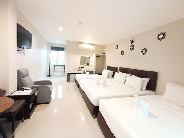 A hotel room with two beds, a desk, a chair, a TV, and a bathroom.